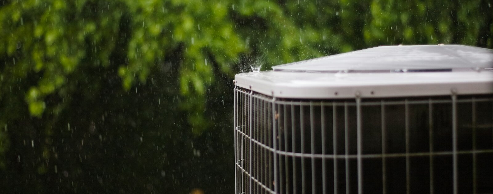 Outdoor AC condenser in a rainstorm — Airo provides 24/7 emergency HVAC service in Tulsa